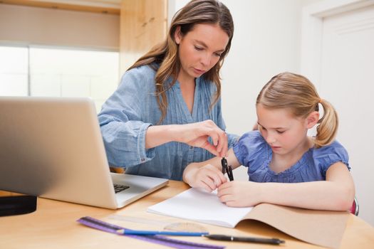 Woman helping her daughter doing her homework in a kitchen