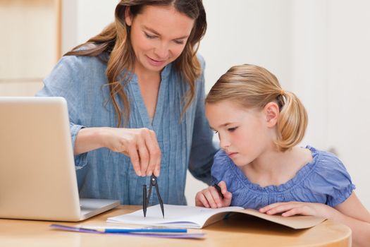 Mother helping her daughter doing her homework in a kitchen