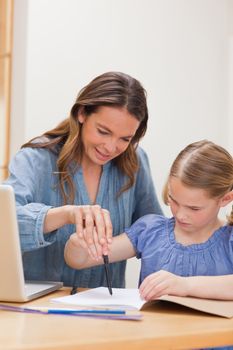 Portrait of a mother helping her daughter doing her homework in a kitchen