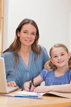 Portrait of a beautiful woman helping her daughter doing her homework in a kitchen