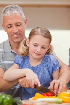 Portrait of a father showing his daughter how to cook in a kitchen