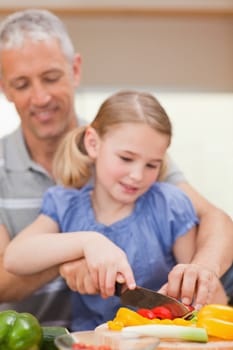 Portrait of a father slicing pepper with his daughter in a kitchen