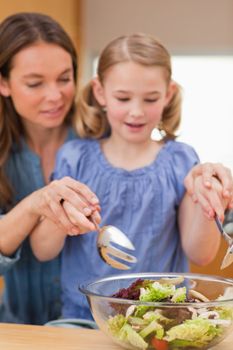 Portrait of a woman preparing a salad with her daughter in a kitchen