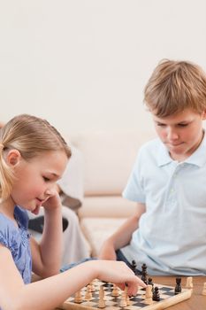 Portrait of siblings playing chess in a living room