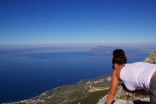 Girl looking down from mountain in picturesque nature park Biokovo on Dalmatian coast near Makarska Riviera in Croatia