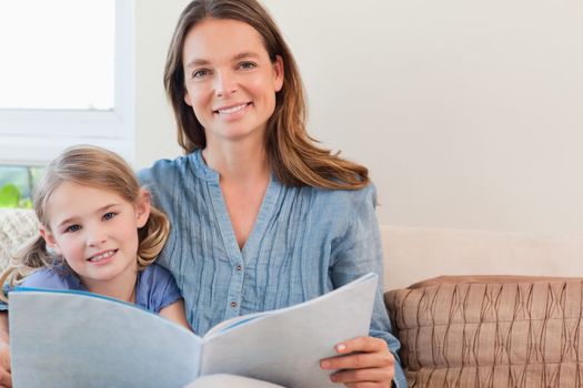 Happy mother reading a book to her daughter in a living room