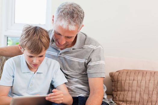 Father and his son using a tablet computer in a living room