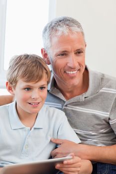 Portrait of a smiling father and his son using a tablet computer in a living room