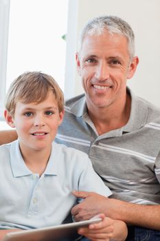 Portrait of a delighted father and his son using a tablet computer in a living room