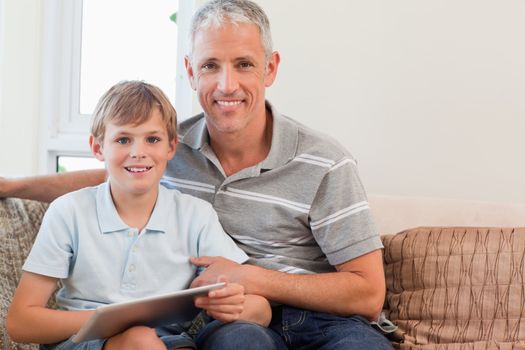 Smiling father and his son using a tablet computer in a living room