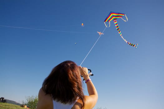 Young girl playing with colorful flying kite on sunny autumn day