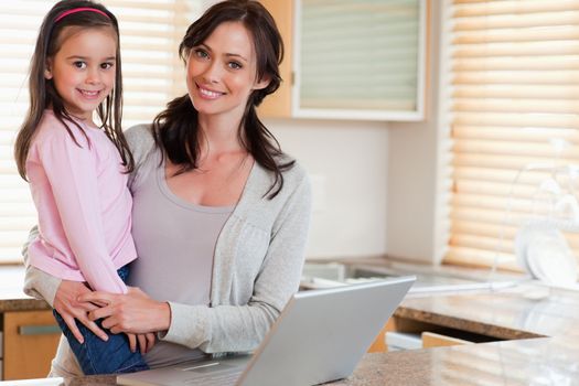 Girl and her mother using a notebook in a kitchen