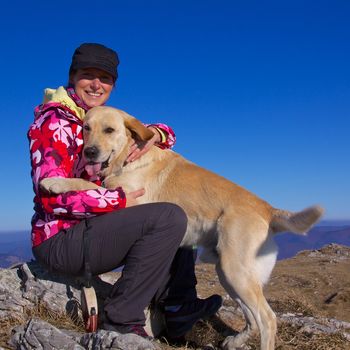 Pretty young girl cuddling with her dog on a sunny autumn day