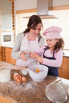 Portrait of a mother and her happy daughter baking in a kitchen