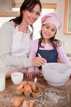 Portrait of a happy mother baking with her daughter in a kitchen