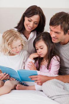 Portrait of a family reading a book in a bedroom