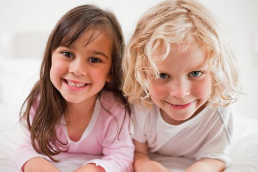 Siblings lying on their bellies in a bedroom