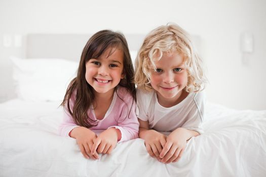 Children lying on their bellies in a bedroom