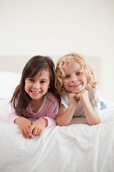 Portrait of children lying on their bellies in a bedroom