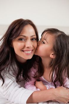 Portrait of a girl kissing her mother in a bedroom