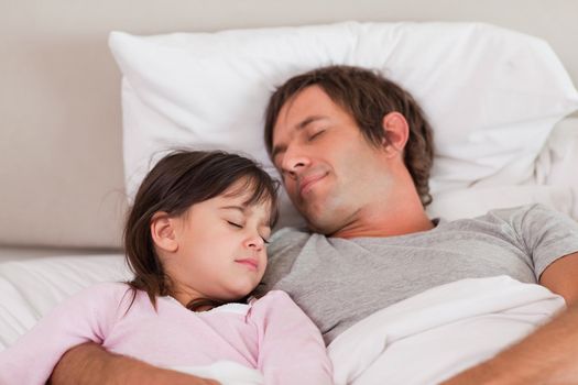 Father sleeping with his daughter in a bedroom