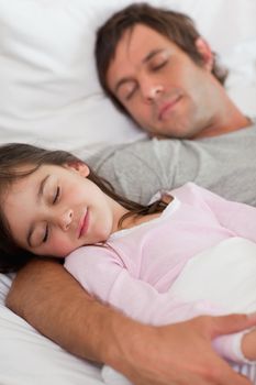 Portrait of a father sleeping with his daughter in a bedroom