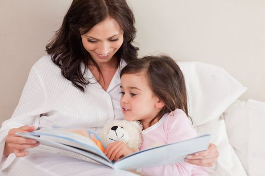 Mother reading a story to her daughter in a bedroom