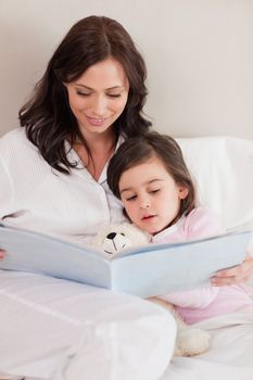 Portrait of a mother reading a story to her daughter in a bedroom