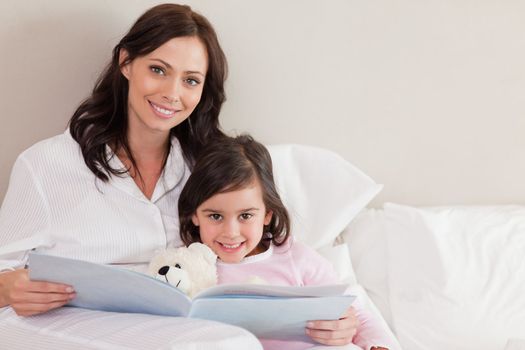 Happy mother reading a story to her daughter in a bedroom