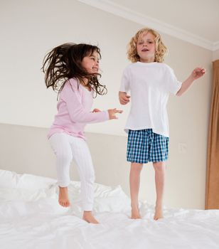 Portrait of siblings jumping on a bed
