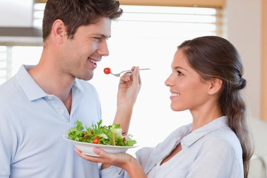 Woman feeding her husband in their kitchen
