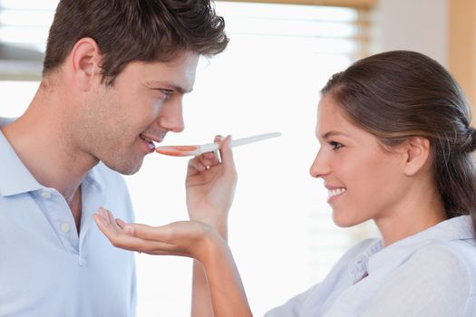 Close up of a man tasting his wife's sauce in their kitchen