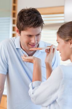 Portrait of a handsome man tasting his wife's sauce in their kitchen