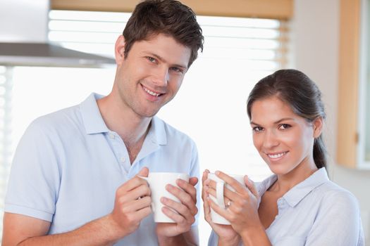 Happy couple drinking coffee in their kitchen