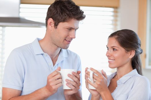Happy couple drinking tea while looking at each other