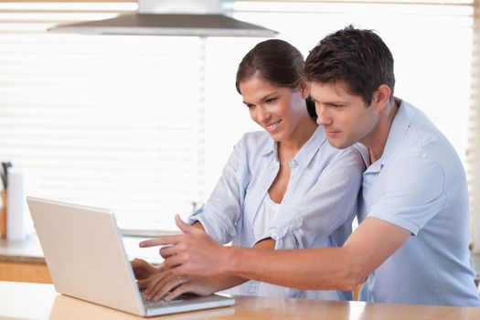 Happy couple using a notebook in their kitchen