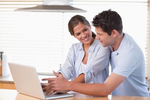Happy couple using a laptop in their kitchen