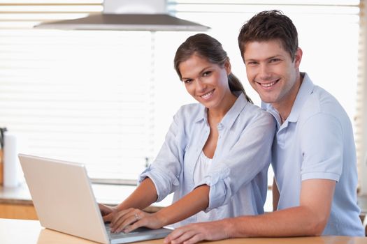 Smiling couple using a laptop in their kitchen