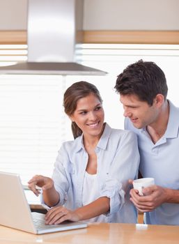 Portrait of a couple using a laptop while having tea in their kitchen
