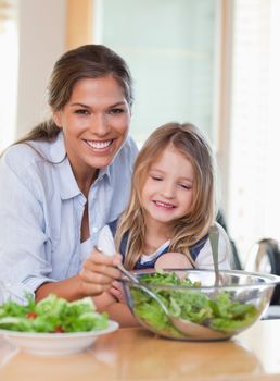 Portrait of a young mother and her daughter preparing a salad in their kitchen