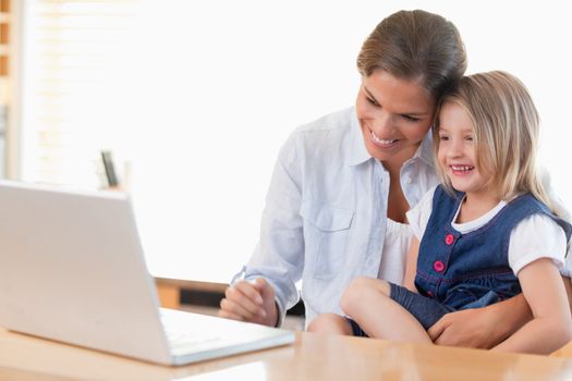 Mother and her daughter using a laptop in their kitchen