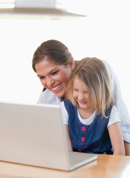 Portrait of a mother and her daughter using a notebook in their kitchen