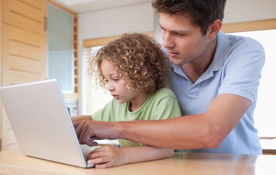 Boy and his father using a laptop in a kitchen