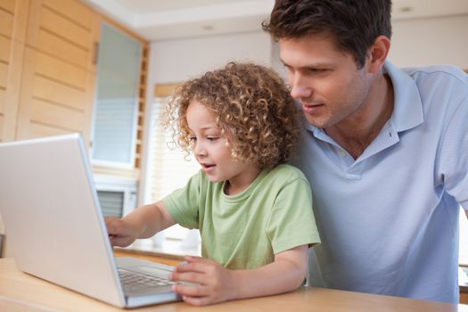 Boy and his father using a notebook in their kitchen