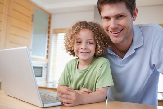 Happy boy and his father using a notebook in their kitchen