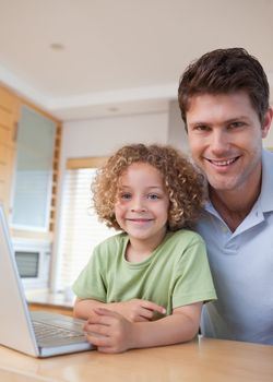 Portrait of a boy and his father using a notebook in their kitchen