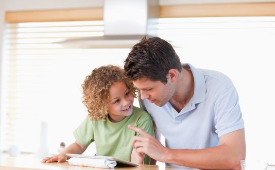 Young boy and his father using a tablet computer in their kitchen
