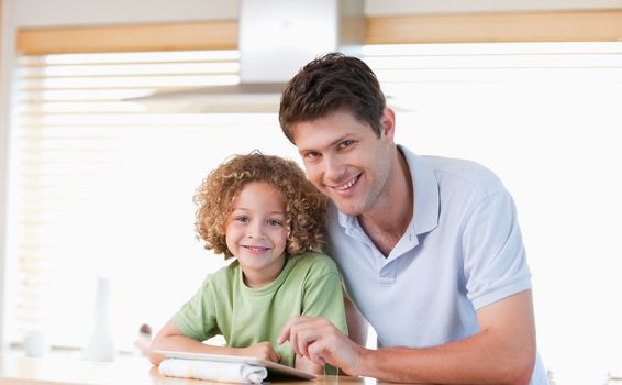 Smiling boy and his father using a tablet computer in their kitchen