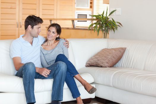 Smiling couple sitting on a couch while looking at each other