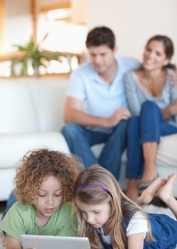 Portrait of children using a tablet computer while their parents are watching in their living room